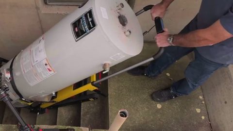 person moving a water heater on a stair-climbing dolly down concrete steps