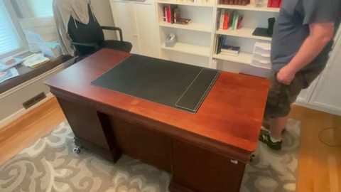 man beside a cherry executive desk on rolling casters in a home office