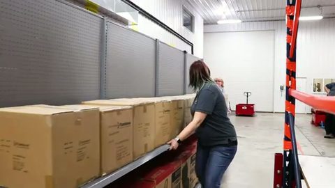 worker pushing a loaded retail shelving unit, back view
